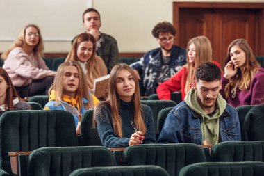 Neşeli mutlu öğrencilerin ders önce bir konferans salonunda oturan Grup