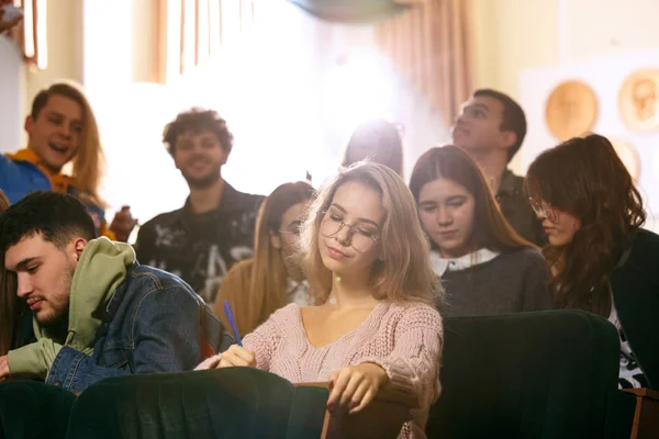 Die Gruppe fröhlich fröhlicher Studenten, die vor dem Unterricht in einem Hörsaal sitzt — Stockfoto