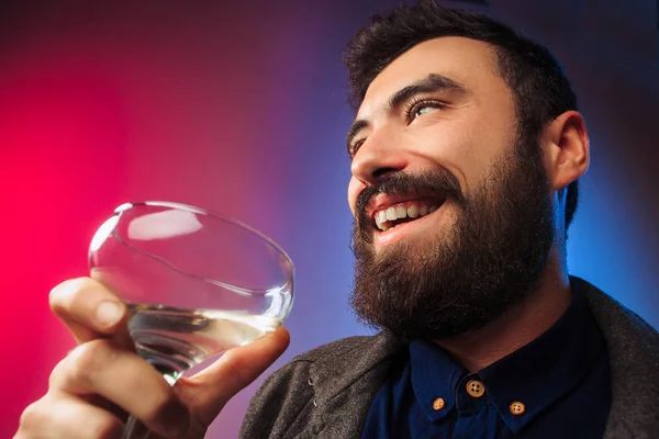 Yllättynyt nuori mies poseeraa viinilasillisen kanssa . — kuvapankkivalokuva