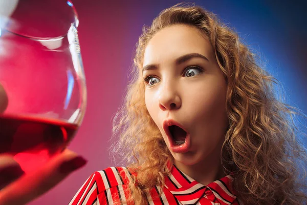 Het verrast jonge vrouw in partij kleding poseren met glas wijn. — Stockfoto