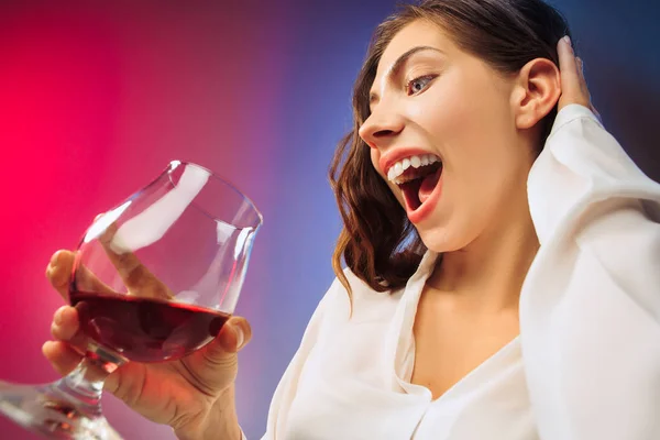 Het verrast jonge vrouw in partij kleding poseren met glas wijn. — Stockfoto