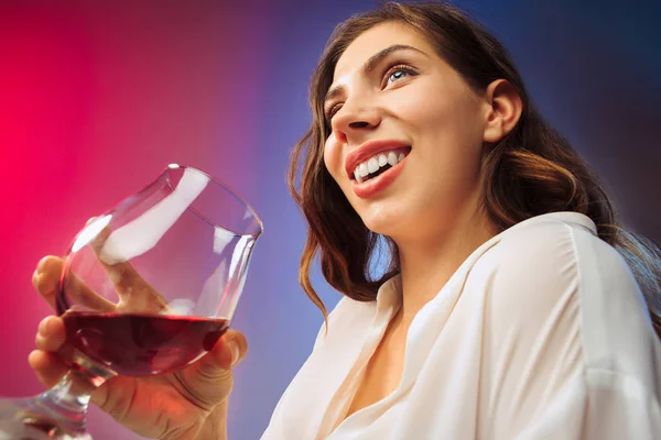 La joven sorprendida en ropa de fiesta posando con un vaso de vino . — Foto de Stock