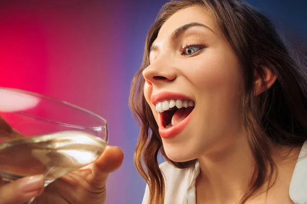 La joven sorprendida en ropa de fiesta posando con un vaso de vino . — Foto de Stock
