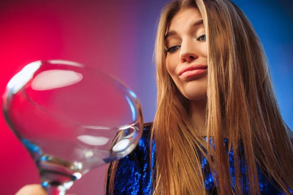 De trieste jonge vrouw in partij kleding poseren met glas wijn. — Stockfoto