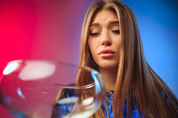 De trieste jonge vrouw in partij kleding poseren met glas wijn. — Stockfoto