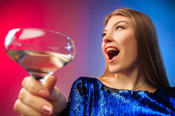 Het verrast jonge vrouw in partij kleding poseren met glas wijn. — Stockfoto