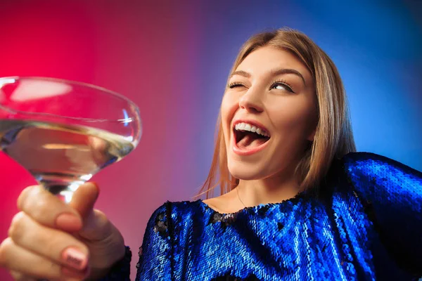 Het verrast jonge vrouw in partij kleding poseren met glas wijn. — Stockfoto