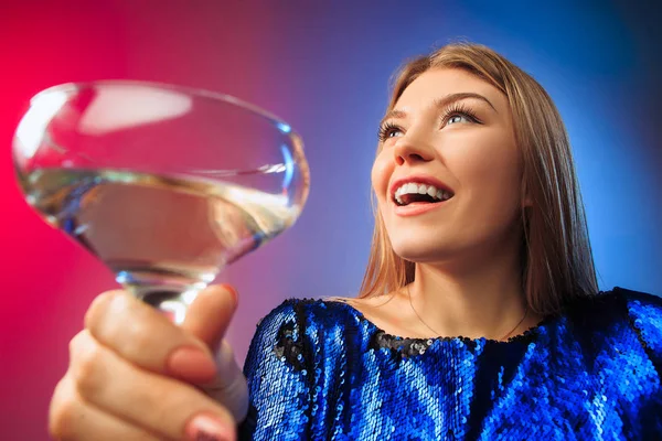 La joven sorprendida en ropa de fiesta posando con un vaso de vino . — Foto de Stock