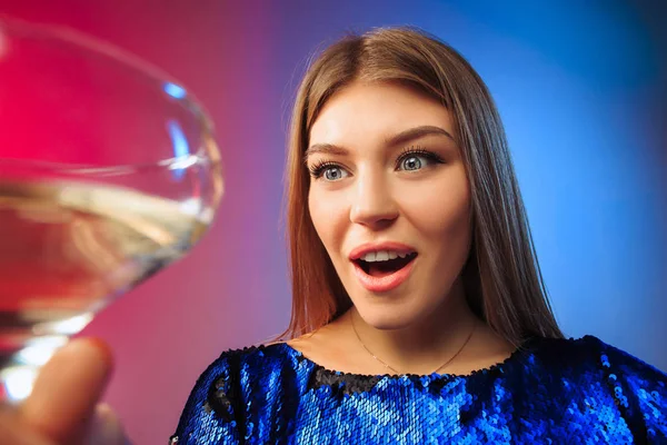 Het verrast jonge vrouw in partij kleding poseren met glas wijn. — Stockfoto