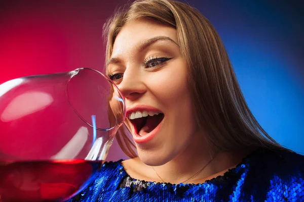La joven sorprendida en ropa de fiesta posando con un vaso de vino . — Foto de Stock
