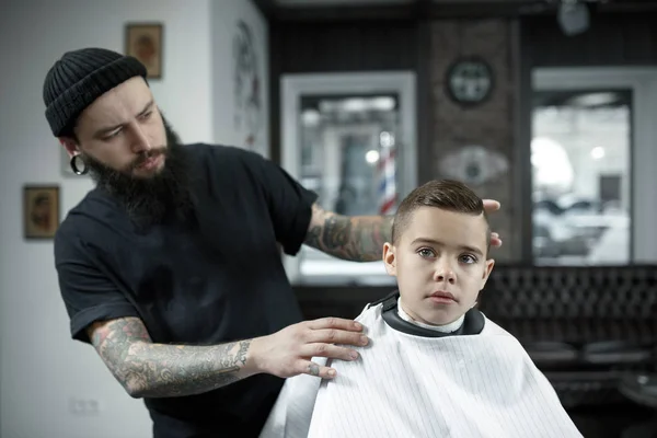 Coiffeur enfants coupant petit garçon sur un fond sombre . — Photo