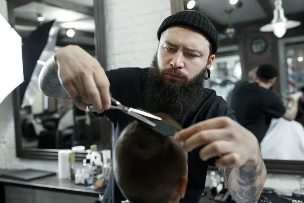 Kinderen kapper knippen jongetje tegen een donkere achtergrond. — Stockfoto