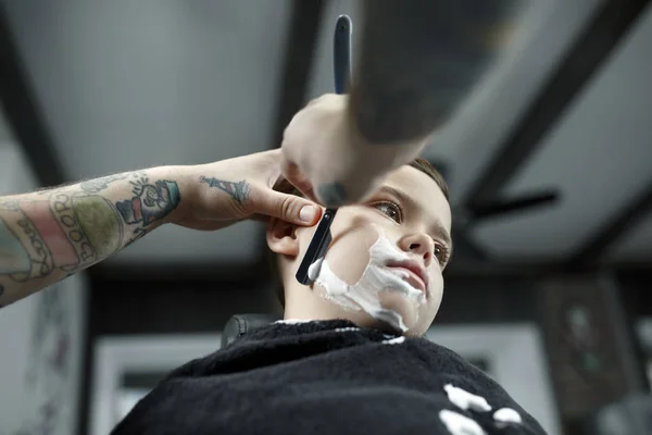 Kinderen kapper knippen jongetje tegen een donkere achtergrond. — Stockfoto