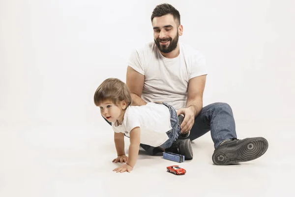 Família feliz com criança sentada junto e sorrindo para a câmera isolada no branco — Fotografia de Stock