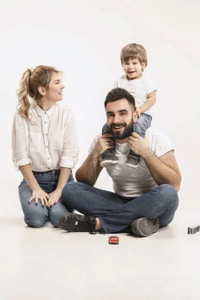 Familia feliz con el niño sentado juntos y sonriendo a la cámara aislado en blanco — Foto de Stock