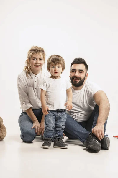 Šťastná rodina s dítětem sedět pohromadě a usmívá se na kameru izolované na bílém — Stock fotografie