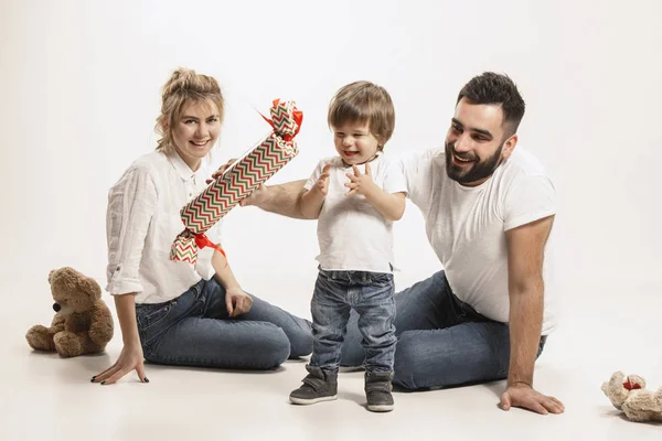 Šťastná rodina s dítětem sedět pohromadě a usmívá se na kameru izolované na bílém — Stock fotografie
