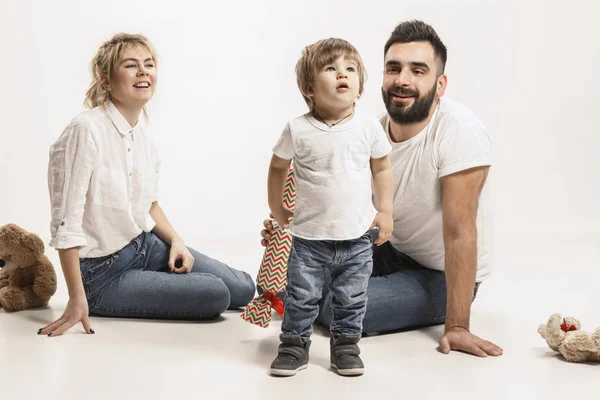 Familia feliz con el niño sentado juntos y sonriendo a la cámara aislado en blanco — Foto de Stock