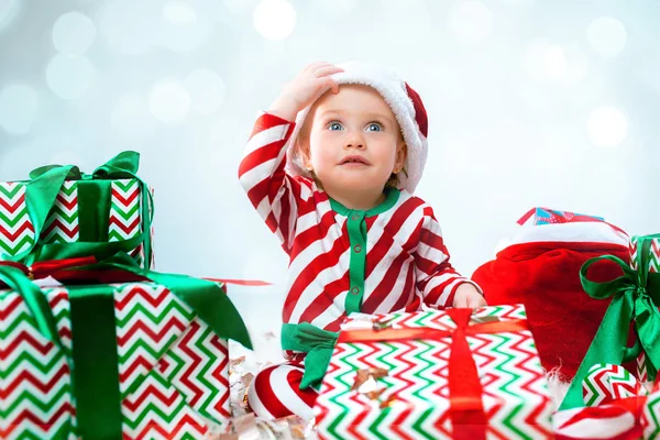 Χαριτωμένο μωρό κορίτσι 1 χρονών φοράει καπέλο santa ποζάρει πάνω από Χριστούγεννα φόντο. Κάθεται στο πάτωμα με Χριστουγεννιάτικη μπάλα. Περίοδος διακοπών. — Φωτογραφία Αρχείου