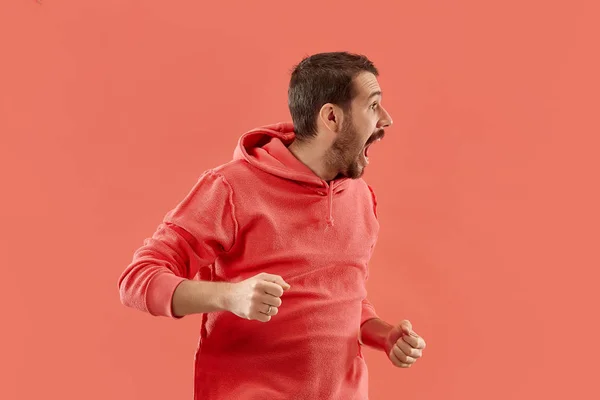 The young emotional angry man screaming on coral studio background — Stock Photo, Image