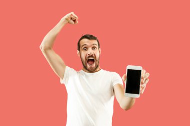 Yakışıklı delikanlı mercan arka planda bir sürpriz yüz ile tahıl balyaları izole smartphone ekran gösterilen