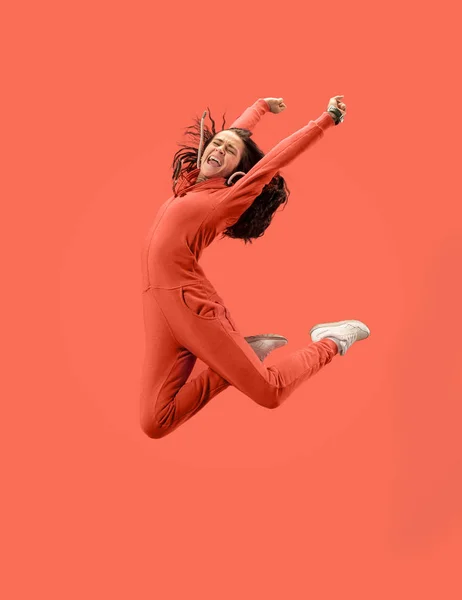 Freedom in moving. Pretty young woman jumping against coral background — Stock Photo, Image