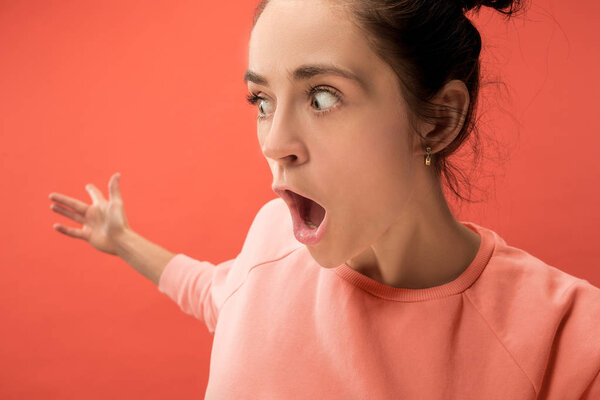 Beautiful woman looking suprised isolated on coral