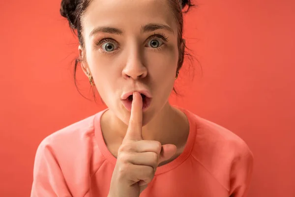 La giovane donna sussurra un segreto dietro la mano sullo sfondo di corallo — Foto Stock