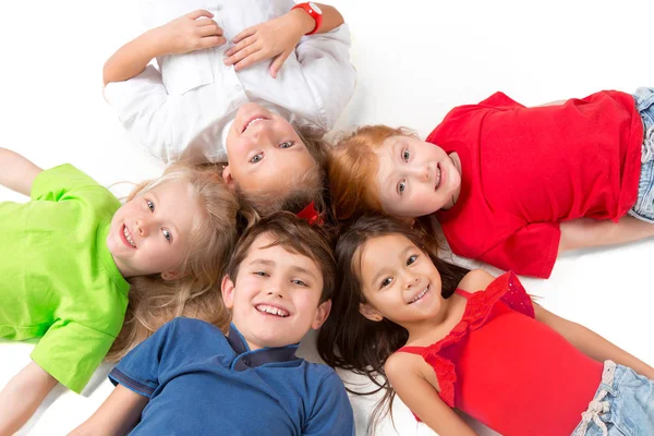 Primer plano de niños felices tumbados en el suelo en el estudio y mirando hacia arriba — Foto de Stock