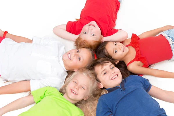 Close-up of happy children lying on floor in studio and looking up — Stock Photo, Image