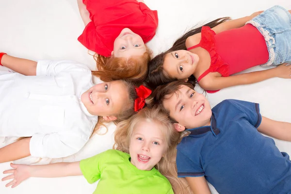 Primer plano de niños felices tumbados en el suelo en el estudio y mirando hacia arriba — Foto de Stock