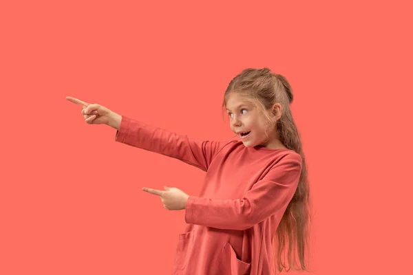 Süßes kleines überraschtes Mädchen im Korallenkleid mit langen Haaren, das in die Kamera lächelt — Stockfoto