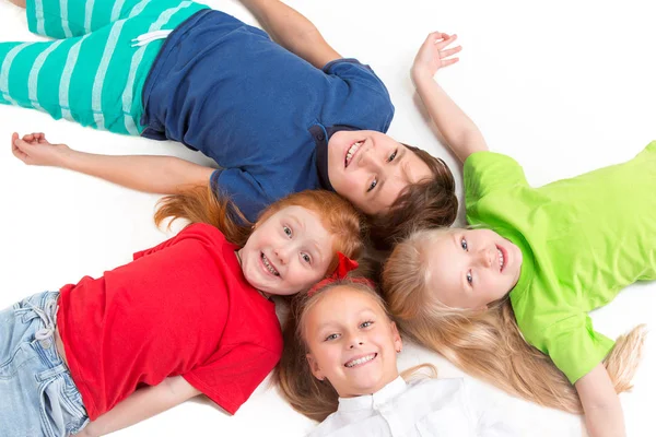 Close-up of happy children lying on floor in studio and looking up Stock Photo