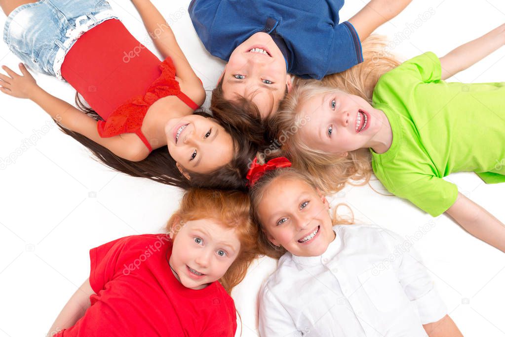 Close-up of happy children lying on floor in studio and looking up