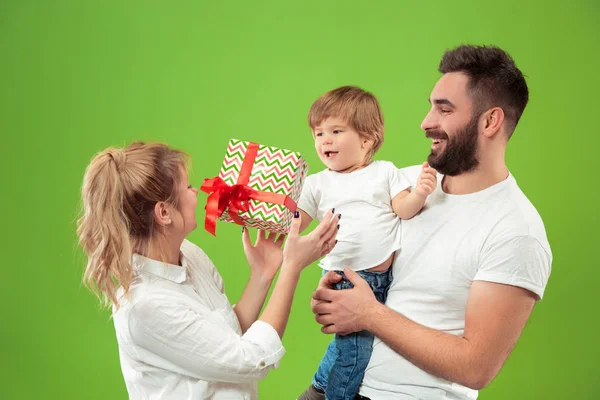 Familia feliz con el niño juntos y sonriendo a la cámara aislada en verde — Foto de Stock