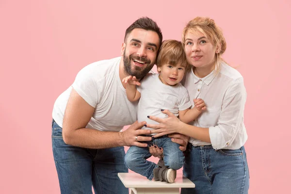 Familia feliz con el niño juntos y sonriendo a la cámara aislada en rosa — Foto de Stock