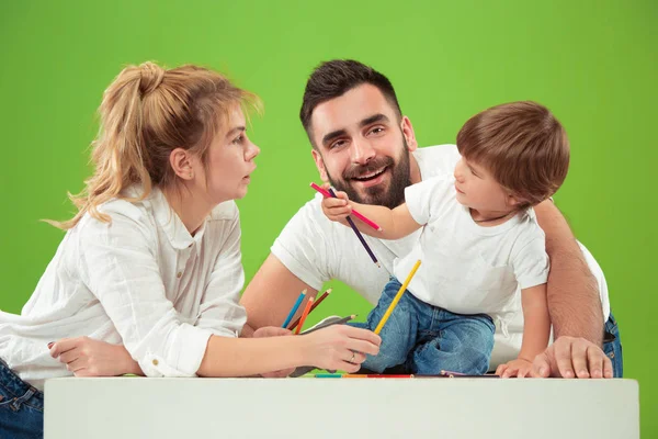 Família feliz com criança juntos e sorrindo para a câmera isolada no verde — Fotografia de Stock