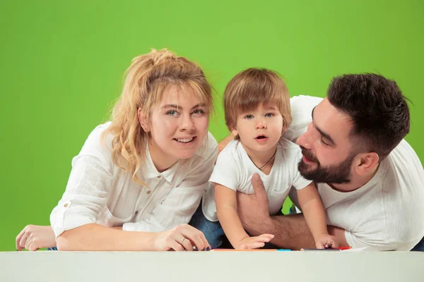 Familia feliz con el niño juntos y sonriendo a la cámara aislada en verde —  Fotos de Stock