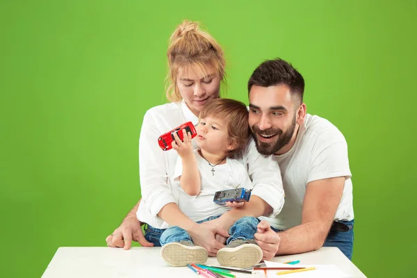 Familia feliz con el niño juntos y sonriendo a la cámara aislada en verde — Foto de Stock