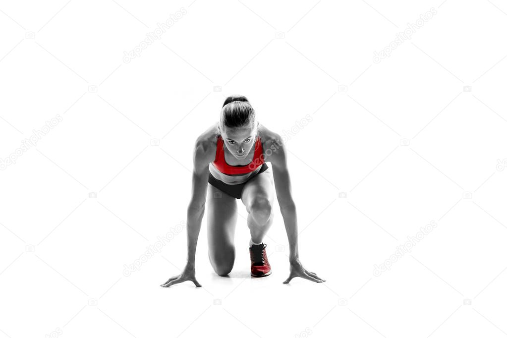 Portrait of young sporty woman at starting block of race isolated over white studio background. The sprinter, jogger, exercise, workout, fitness, training, jogging concept.