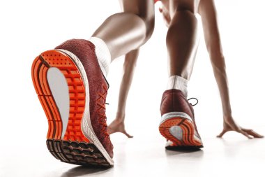 Beyaz arka plan üzerinde izole yarışın başlangıç bloğundaki genç sportif kadın portresi