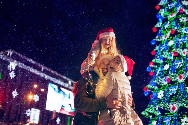 Familia, Navidad, vacaciones, temporada y concepto de personas - familia feliz sobre el fondo de la ciudad y la nieve —  Fotos de Stock