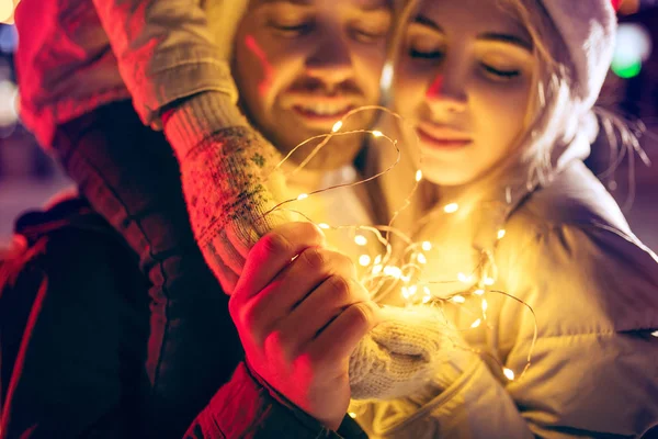 成年夫妇在圣诞节期间在城市徘徊在灯光城市背景和雪在晚上 — 图库照片
