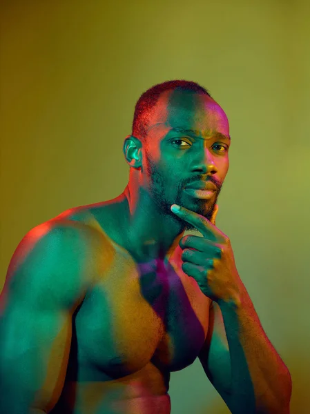 Close up portrait of a young naked african man looking at camera indoors