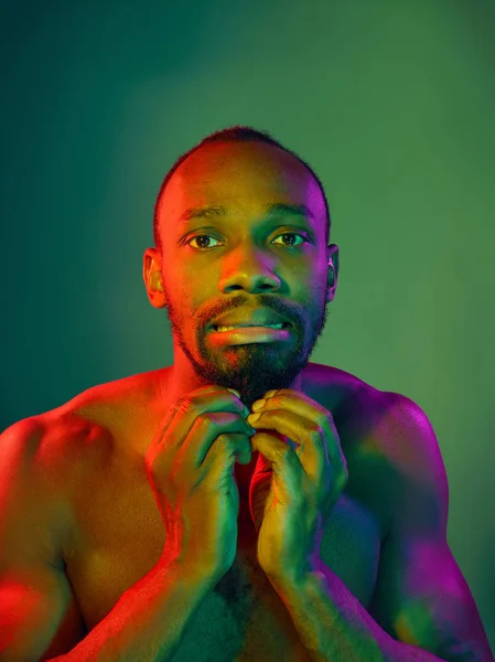 Close up portrait of a young naked african man looking at camera indoors