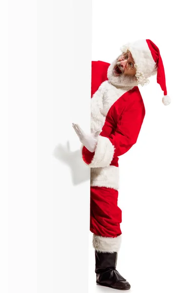 Счастливый Санта-Клаус на фоне рекламного баннера с копировальным пространством. Улыбающийся Санта Клаус указывает белым пустым знаком — стоковое фото