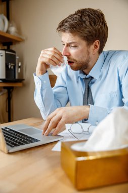 Ofiste çalışırken burnunu silen mendili olan hasta bir adam, iş adamı soğuk algınlığına yakalandı, mevsimsel grip. Salgın hastalık, hastalık önleme, ofisteki klima hastalığa neden oluyor.