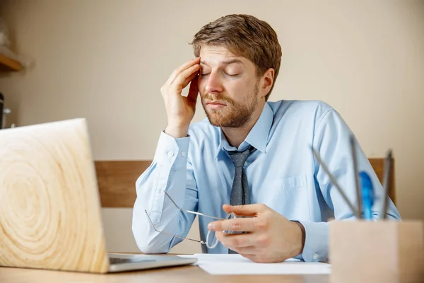病気や疲れを感じています イライラ悲しい不幸な病気の若い男のオフィスで彼の仕事場に座って頭をマッサージします 季節性インフルエンザ 新型インフルエンザ 病気予防の概念 — ストック写真