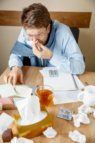 Sick man while working in office, businessman caught cold, seasonal flu.