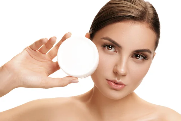 Menina bonito se preparando para começar o dia. Ela está aplicando creme hidratante no rosto . — Fotografia de Stock